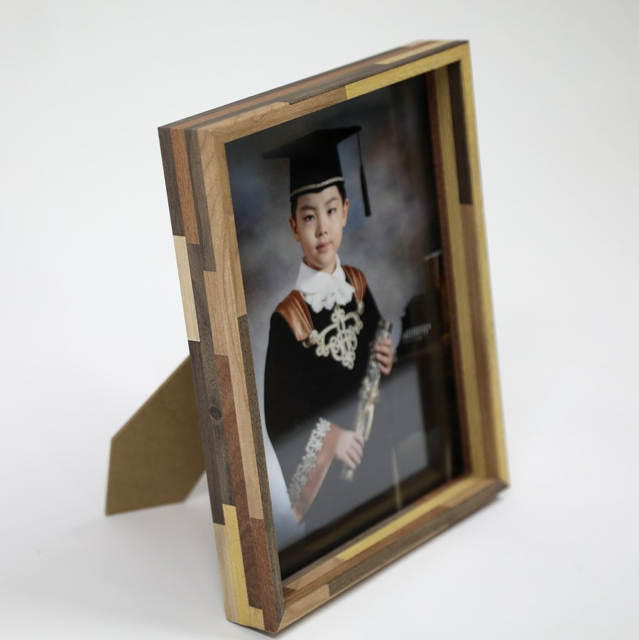 졸업사진이 든 원목 액자 한 점을 세워 둔 모습